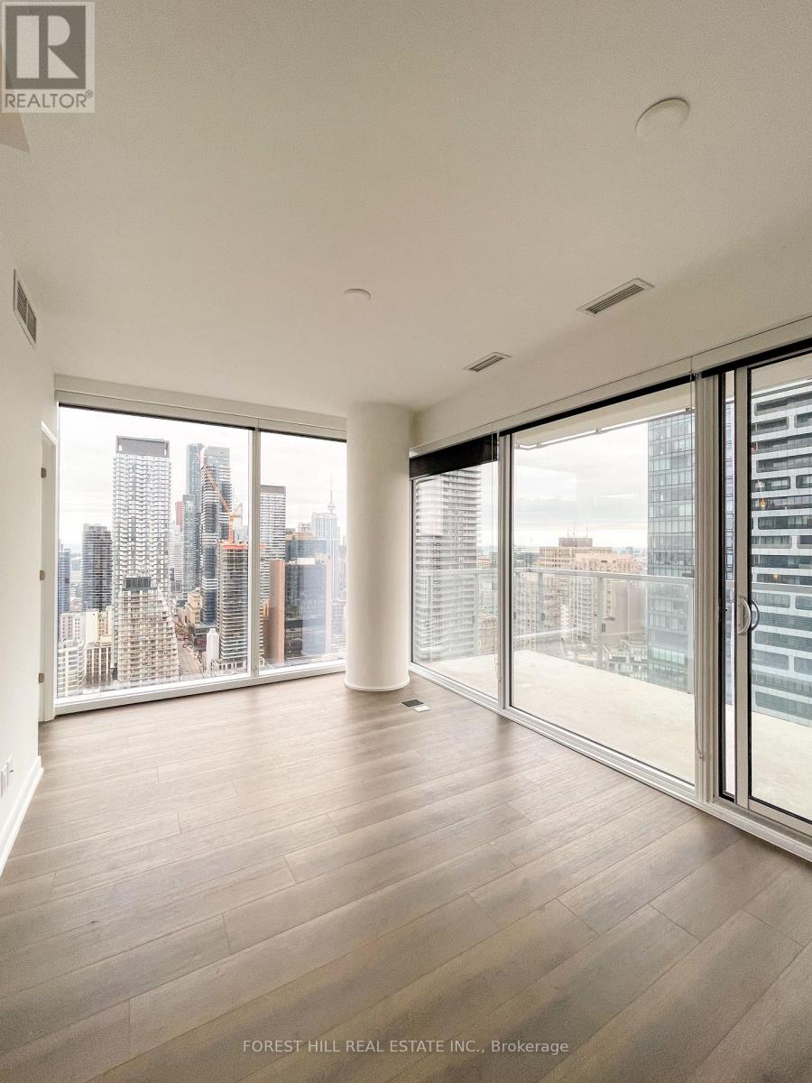 A spacious room with wooden floors and large windows overlooking a cityscape.