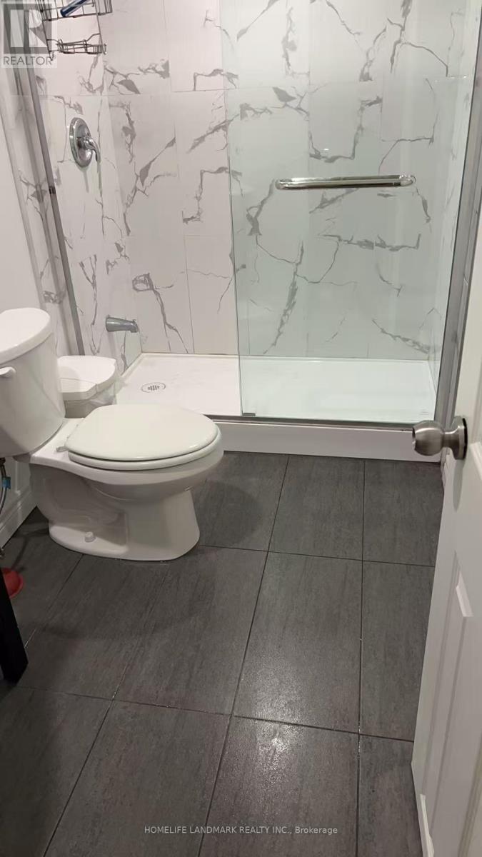 A white toilet in a bathroom with a marble wall.