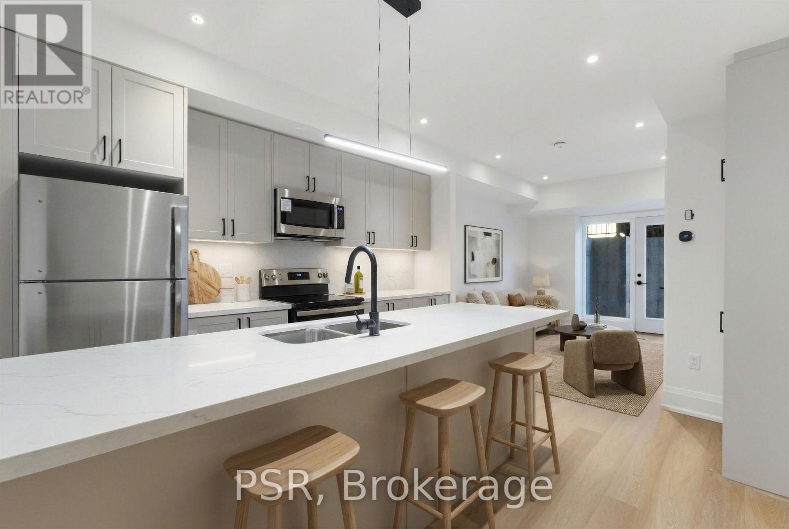 A modern kitchen with stainless steel appliances and wooden stools.