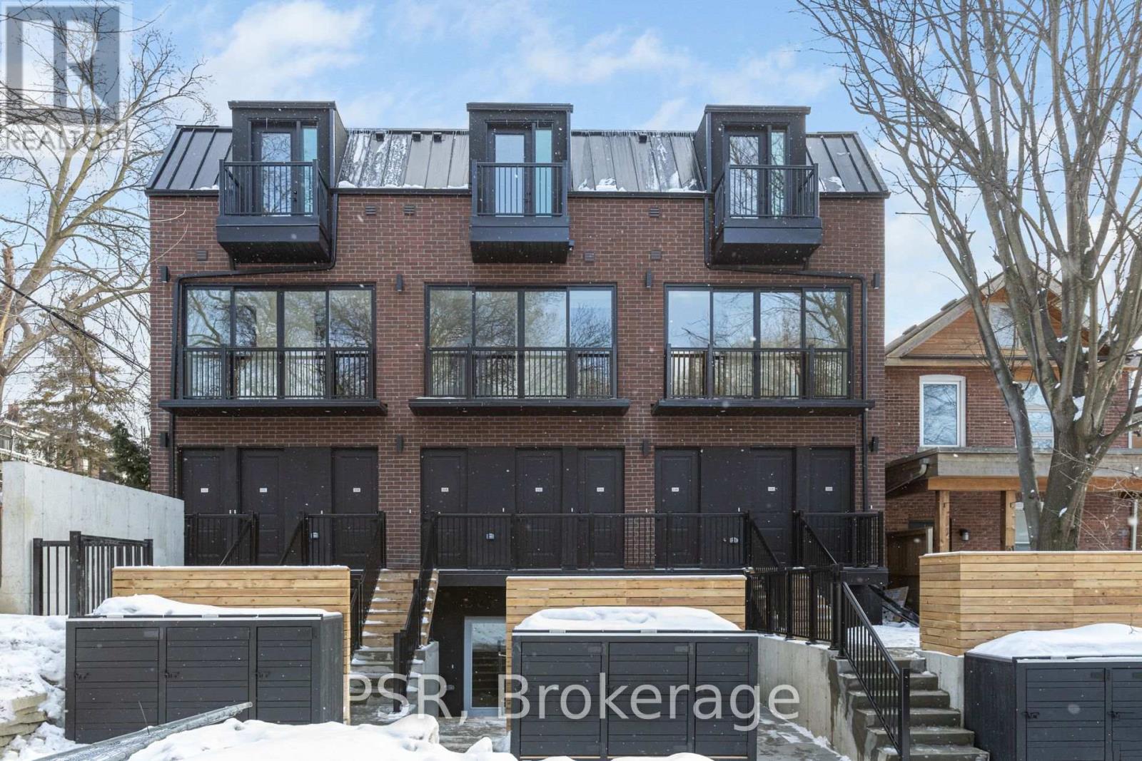 A modern brick building with black windows and balconies.