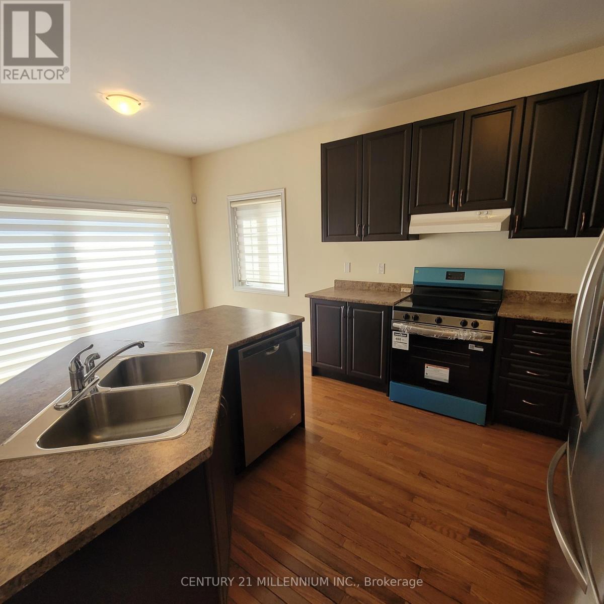 A kitchen with wooden floors and black cabinets.