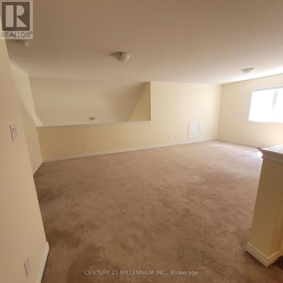 A large empty room with a carpeted floor and a window.