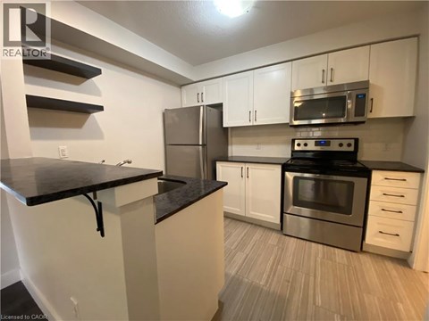 A kitchen with white cabinets and a black countertop.