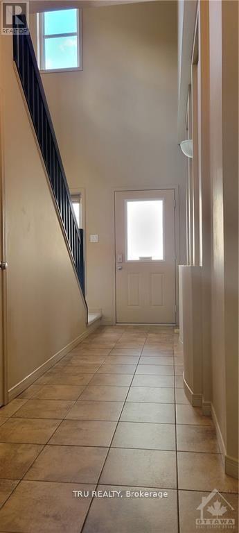 A hallway with tiled floors and a staircase with a railing.