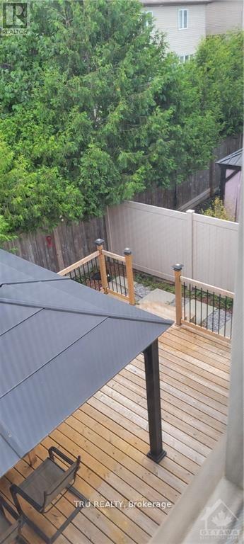 A wooden deck with a blue umbrella and a view of a green tree and a white building.