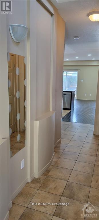 A hallway with a tiled floor and a light on the wall.