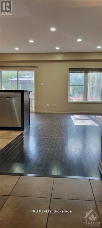 A modern kitchen with a stainless steel refrigerator and wooden flooring.
