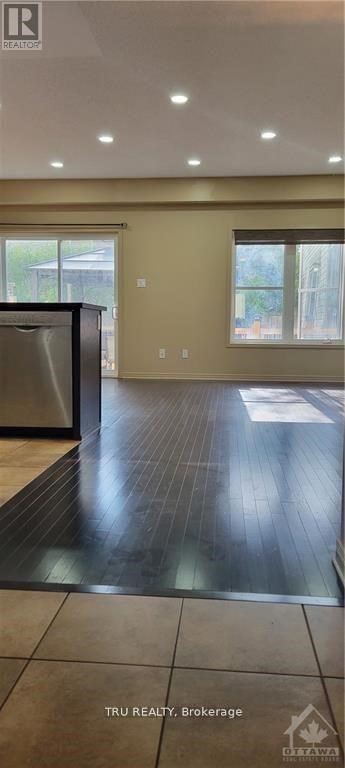 A modern kitchen with a stainless steel refrigerator and wooden flooring.