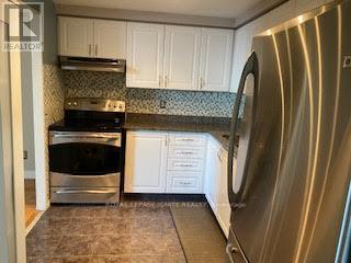 A stainless steel dishwasher is in a kitchen with white cabinets.
