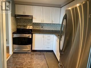 A stainless steel dishwasher is in a kitchen with white cabinets.