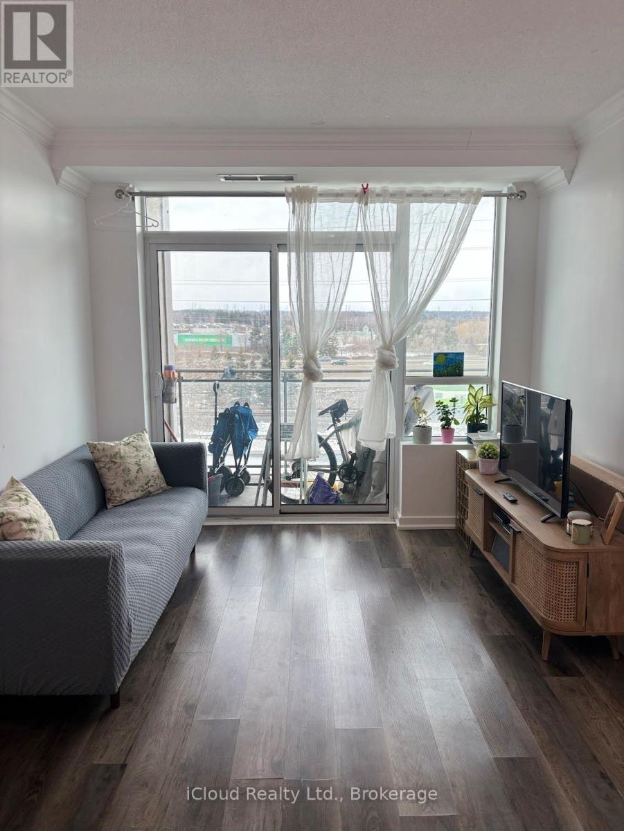A living room with a grey couch, a wooden cabinet, and a large window with a view of the city.