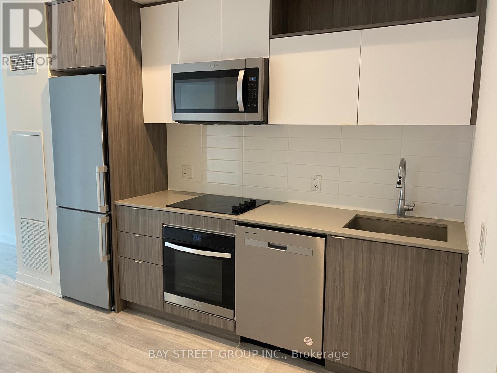 A modern kitchen with a refrigerator, oven, and microwave.