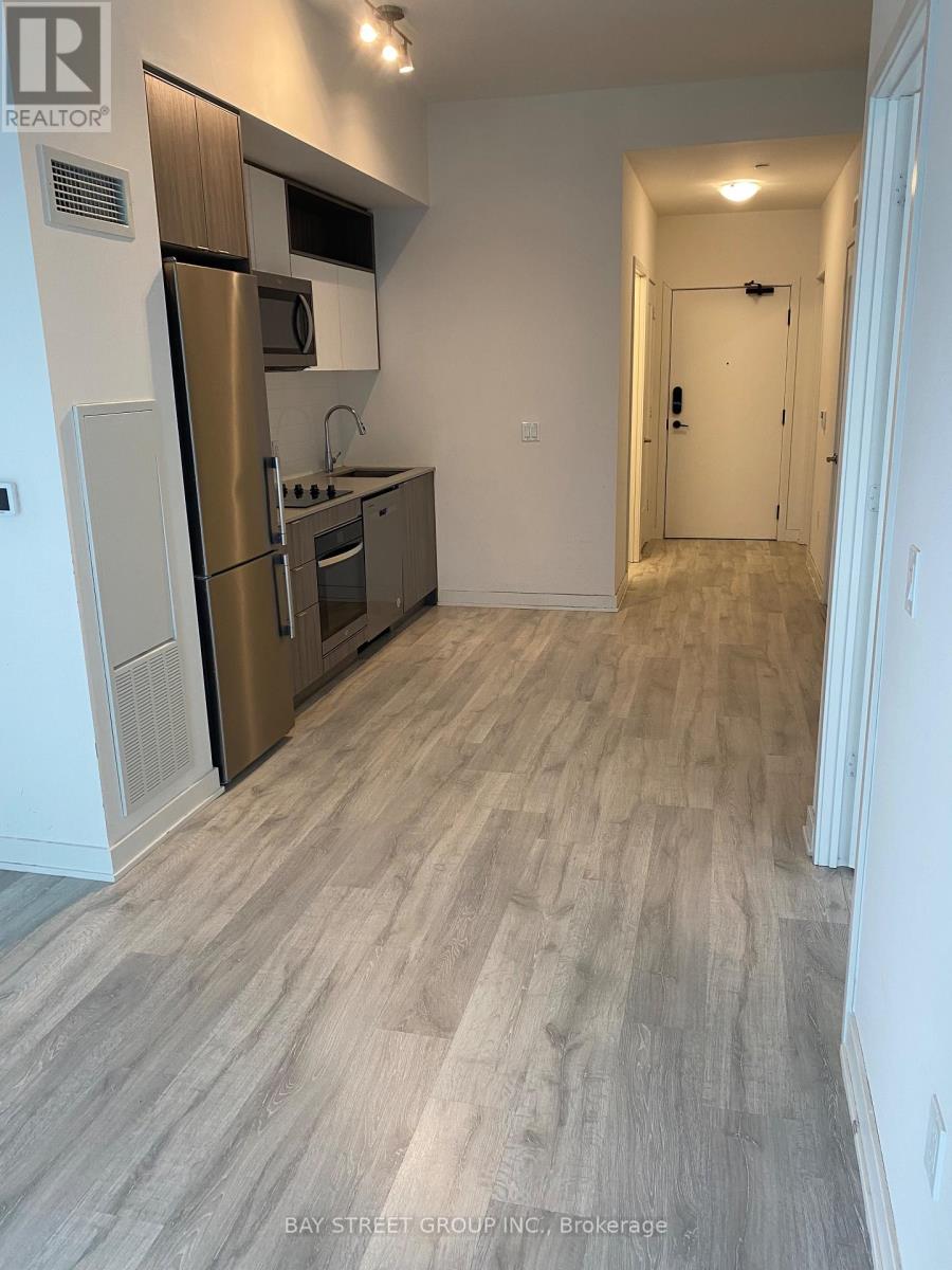 A kitchen with a refrigerator, oven, and microwave.