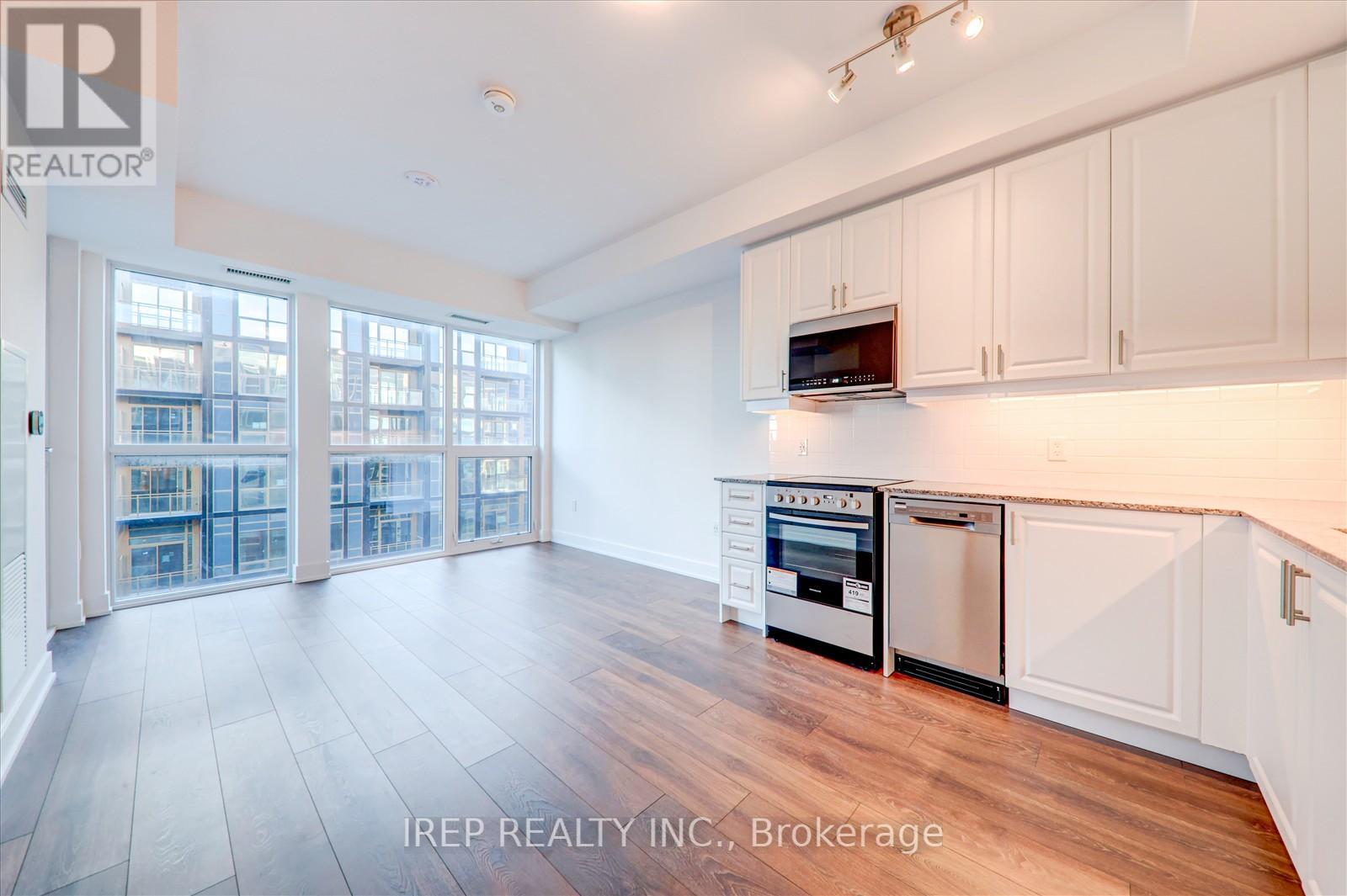 A kitchen with white cabinets and a wooden floor.