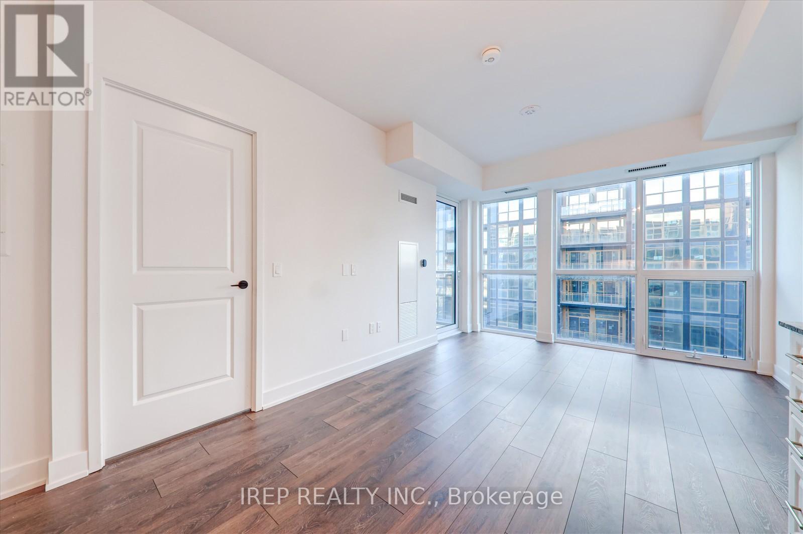 A spacious room with wooden floors and a view of a cityscape through large windows.