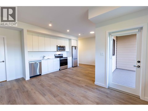 A kitchen with white cabinets and a wooden floor.