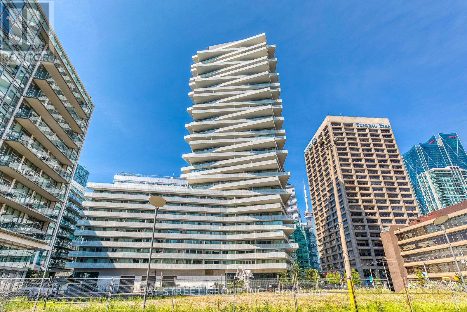 A tall, modern building with a unique design stands out in a cityscape.