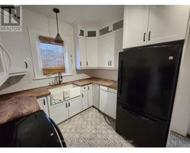 A black refrigerator is in a kitchen with white cabinets.