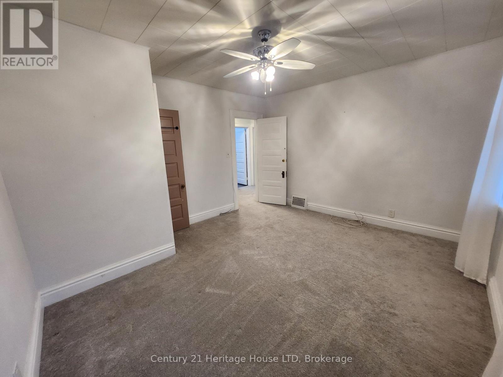 A spacious room with a ceiling fan and carpeted floor.