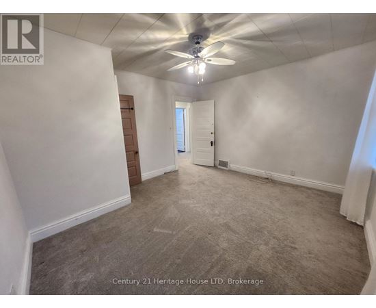 A spacious room with a ceiling fan and carpeted floor.