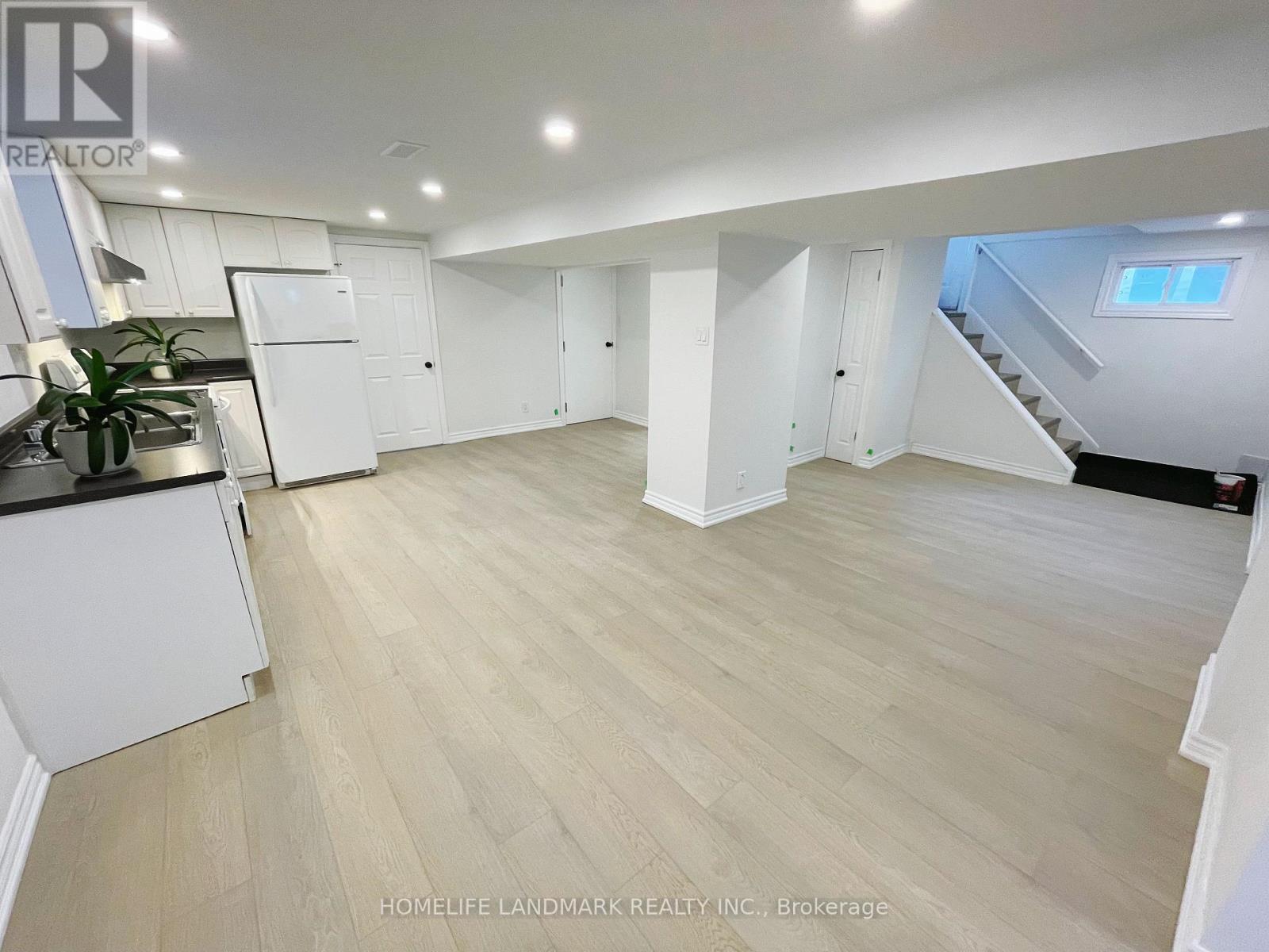 A spacious room with light wood flooring and white walls.