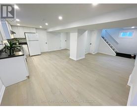 A spacious room with light wood flooring and white walls.