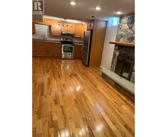 A kitchen with wooden floors and a stone fireplace.