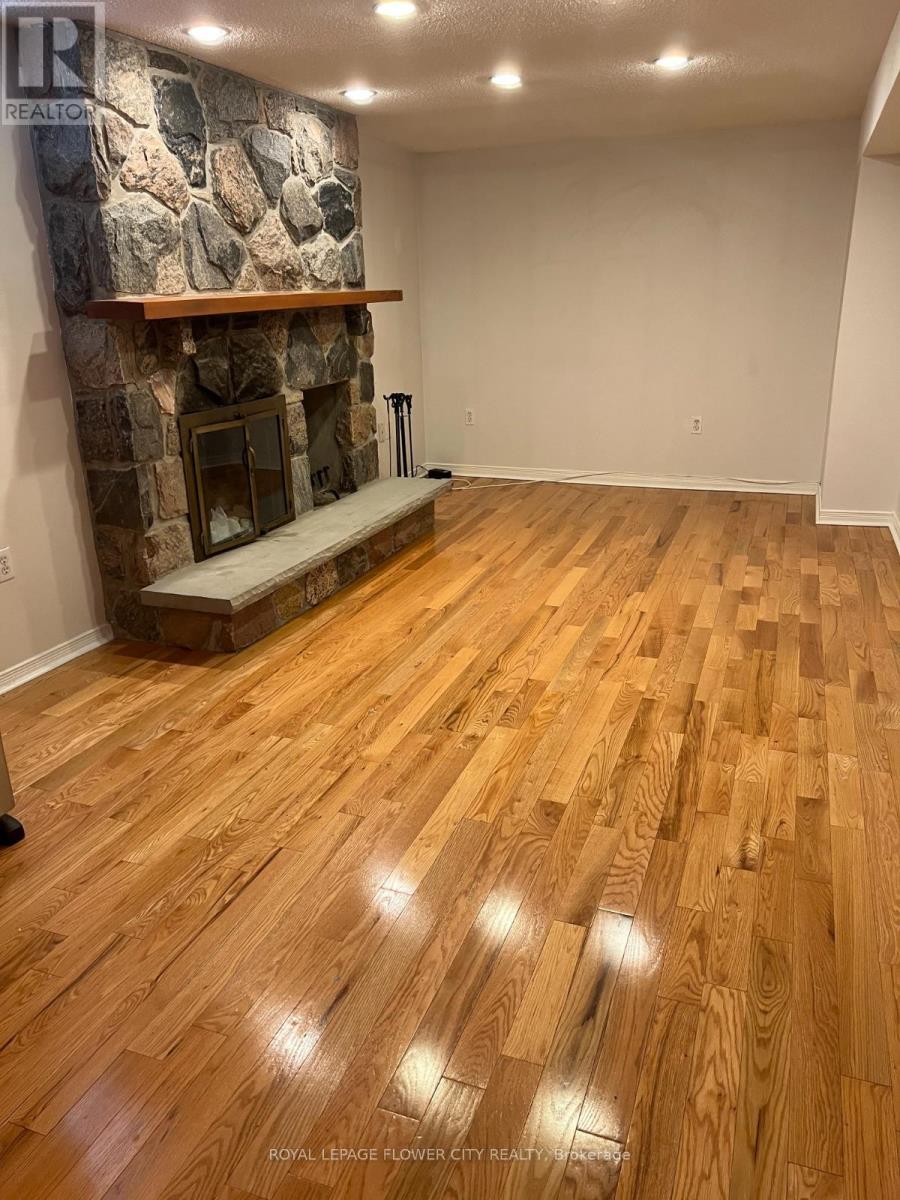 A room with a stone fireplace and wooden flooring.