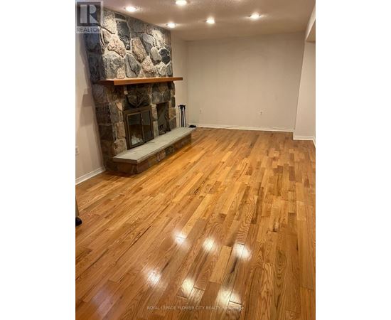 A room with a stone fireplace and wooden flooring.