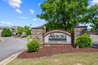 the arbors apartments entrance sign in front of tree and building