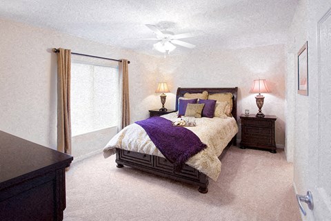 A bedroom with a bed, nightstands, and a ceiling fan.