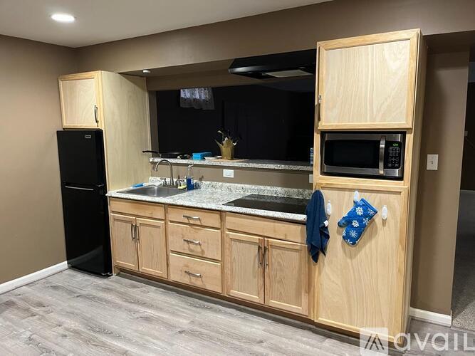 A kitchen with wooden cabinets and a black refrigerator.