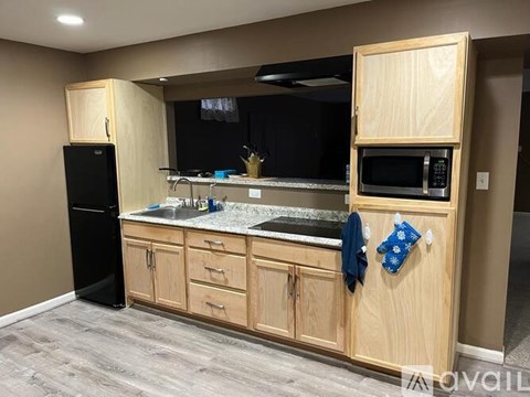 A kitchen with wooden cabinets and a black refrigerator.