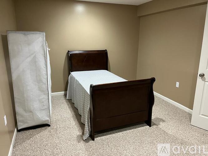 A bedroom with a bed, a wardrobe, and a carpeted floor.