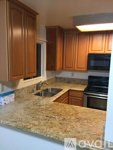 A kitchen with brown cabinets and granite countertops.