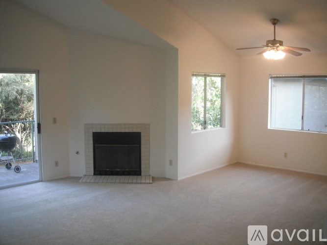 A living room with a fireplace and a ceiling fan.