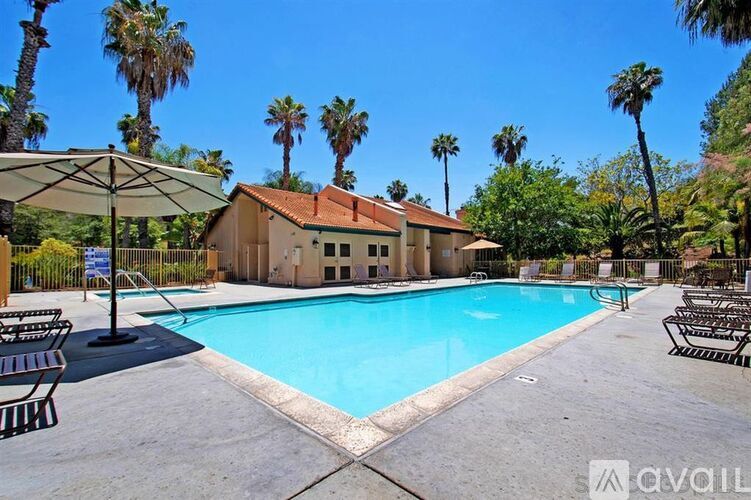 A pool surrounded by palm trees and a building.