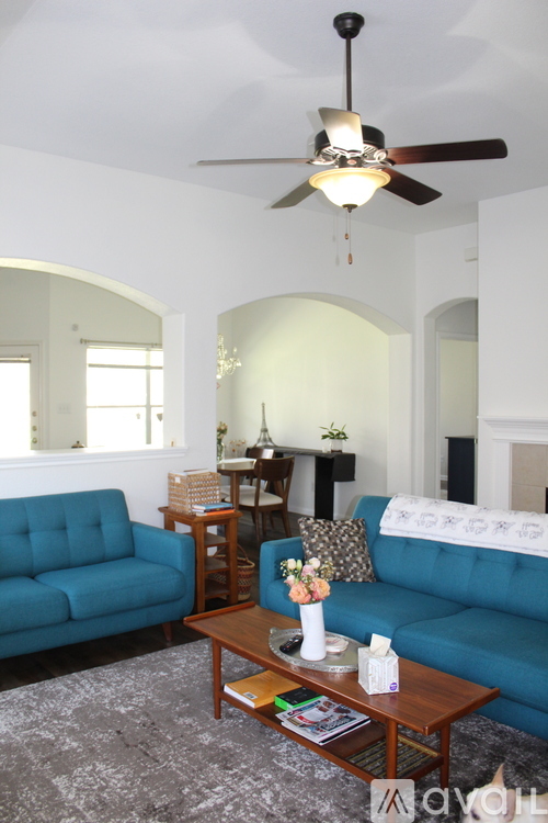 A living room with a blue couch and a ceiling fan.