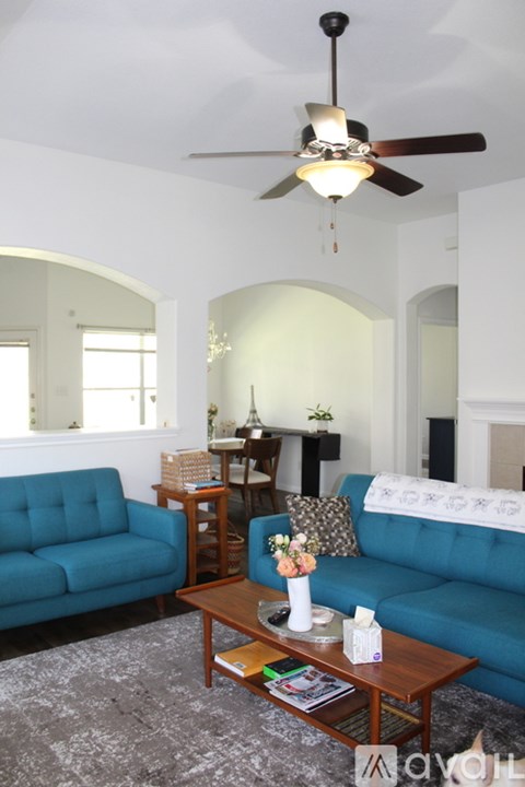 A living room with a blue couch and a ceiling fan.