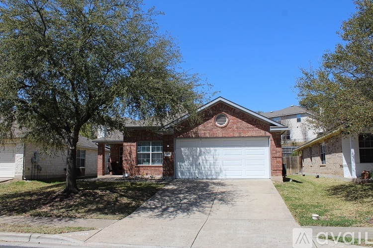 A house with a garage and a tree in front.