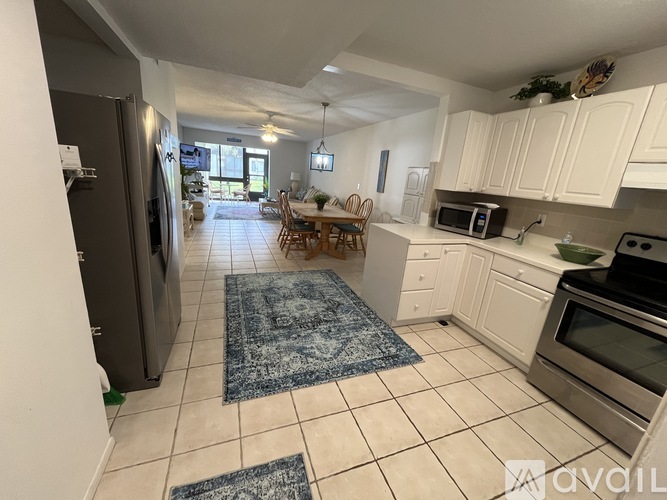 A kitchen with white cabinets and a black fridge.