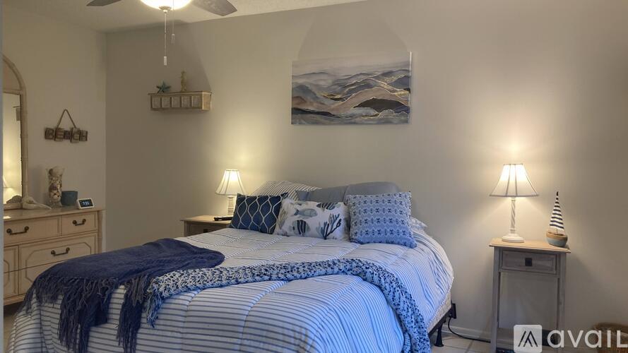 A bedroom with a large bed and a painting on the wall.