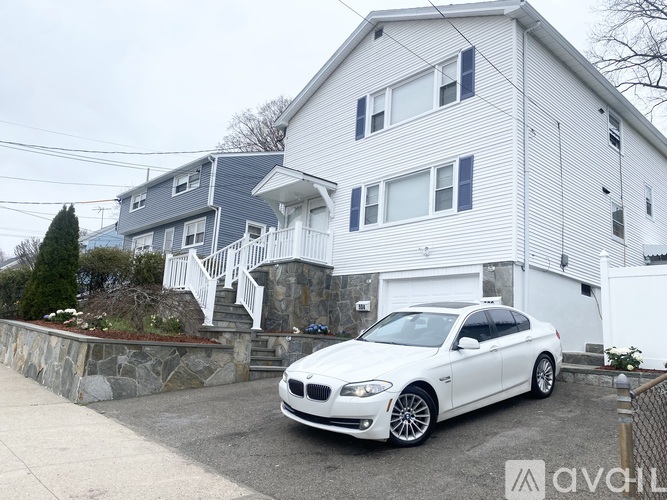 A white car is parked in front of a house.