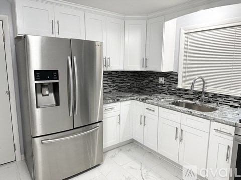 A modern kitchen with a stainless steel refrigerator and white cabinets.