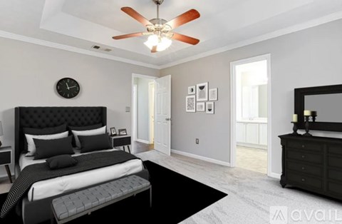 A bedroom with a black bed and a ceiling fan.
