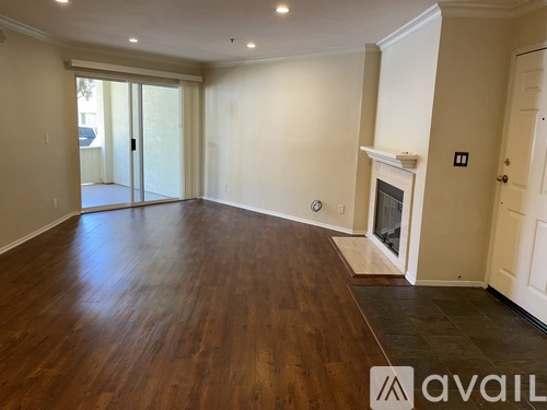 A spacious room with wooden floors and a fireplace.