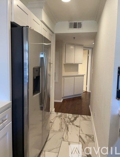 A kitchen with a refrigerator and a marble floor.