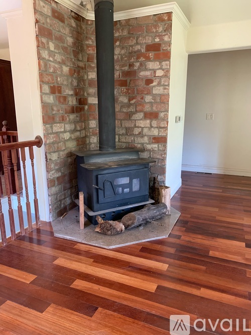 A wood stove is in a room with a brick wall and wooden floors.