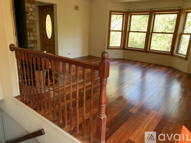 A wooden staircase with a railing leads to a bright room with a window.