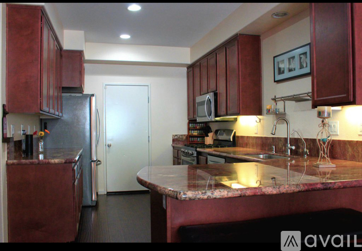 A kitchen with red cabinets and a marble counter top.